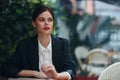 Stylish fashion woman portrait sitting in a cafe at a table and smoking a cigarette releasing smoke from her mouth with Royalty Free Stock Photo