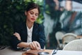 Stylish fashion woman sits in a cafe at a table and smokes a cigarette releasing smoke from her mouth with red lipstick Royalty Free Stock Photo