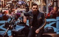 Stylish fashionable biker in sunglasses dressed in a black leather jacket, sitting on his custom-made retro motorcycle Royalty Free Stock Photo