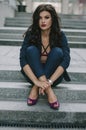 A stylish fashionable brunette in a blue suit is sitting on the steps in the city. Fashion photo Royalty Free Stock Photo
