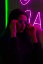 Stylish fashionable teenage girl in glasses with reflection looks up on the street with neon illumination of the city. Royalty Free Stock Photo