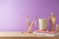 Stylish feminine home office desk with coffee cup, notebook and pencils over purple background. Back to school concept