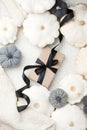 Stylish flat lay with uxury paper craft gift box and black satin ribbon bow on natural pumpkin squash background with copy space,