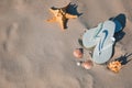 Stylish flip flops, starfish and sea shells on beach, flat lay. Space for text Royalty Free Stock Photo