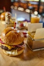 Stylish food photo. Juicy fresh american burger with chips on a wooden underlay. Restaurant setup blurred background