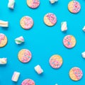 Stylish frame of cookies with pink glaze and marshmallow on blue background. Flat lay. top view. Royalty Free Stock Photo