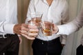 Stylish friends businessmen in suits toasting with glasses of whiskey indoors, closeup. groom`s morning