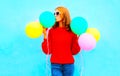 Stylish funny girl kisses an air colorful balloons on a blue