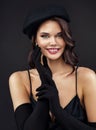 Stylish Girl in Black Beret. Fashion Model in French Hat and Gloves. Happy Young Woman Cheerful Smiling over Dark Background. Royalty Free Stock Photo