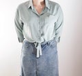 Stylish girl in a blouse with ties at the bottom and a denim skirt on a white background. Shopping and business lady