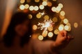 Stylish girl with burning sparkler celebrating in festive dark room. Happy New Year. Happy woman holding firework at christmas Royalty Free Stock Photo