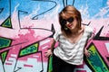 Stylish girl in a dance pose against graffiti wall