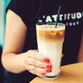 Stylish girl drinking cold latte in cafe. Glass of coffee drink in female hands close up. Summer cold drinks with coffee Royalty Free Stock Photo