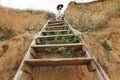 Stylish girl in fashionable look sitting on wooden stairs on beach cliff at sea in sunny light. Happy young boho woman in hat with Royalty Free Stock Photo