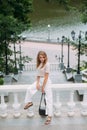 A stylish girl with fashionable make-up and hairstyle stands against the backdrop of a stone staircase in a park Royalty Free Stock Photo