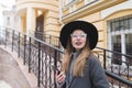 Stylish girl in a hat and glasses against the backdrop of old architecture. Happy girl with braces smiles sincerely Royalty Free Stock Photo
