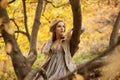 Stylish girl model sitting on a tree branch with one hand props