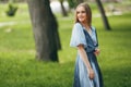 Stylish girl posing in a dress in a sunny spring park. Cheerful, happy portrait of a beautiful girl in the summer Royalty Free Stock Photo