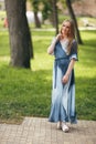 Stylish girl posing in a dress in a sunny spring park. Cheerful, happy portrait of a beautiful girl in the summer Royalty Free Stock Photo