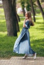 Stylish girl posing in a dress in a sunny spring park. Cheerful, happy portrait of a beautiful girl in the summer Royalty Free Stock Photo