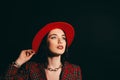 Stylish girl in red dress and hat. portrait of a young girl with long hair. Dark background