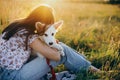 Stylish girl relaxing with her adorable puppy on a picnic. Loyal friend. Happy woman hugging cute white puppy in summer meadow in