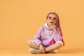Stylish girl in rounded glasses with pink dreadlocks sitting, th Royalty Free Stock Photo