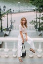 A stylish girl stands against the backdrop of a large stone staircase in a park near a river Royalty Free Stock Photo