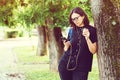 Stylish girl in trendy eye glasses outdoors. Beautiful girl hipster drinks coffee, listens favorite music in park. Hipster girl Royalty Free Stock Photo