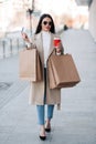 Stylish girl walking with coffee and shopping bags and doing shopping Royalty Free Stock Photo
