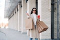 Stylish girl walking with coffee and shopping bags and doing shopping Royalty Free Stock Photo