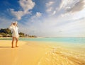 Girl watches the sunset on a tropical palm fringed beach of a maldives island