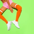 Stylish girl in white Sneakers and vintage orange stockings on yellow fresh minimal background. Sport fitness summer active vibes