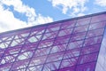 Stylish Glass Facade of Violet Tinted Semi-Transparent Glass Building Against Blue Sky with Sunbeams