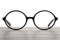 Stylish glasses with black frame on wooden table against white background Royalty Free Stock Photo