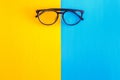 Stylish glasses on a bright blue-cyan and yellow-orange background, top view, isolated. Copy space. Flat lay