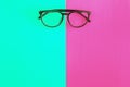 Stylish glasses on a bright green-cyan and crimson-pink background, top view, isolated. Copy space. Flat lay