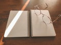 stylish glasses left on a notebook. The sun's rays create a beautiful shadow on the desktop. Blank notebook