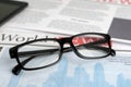 Stylish glasses on newspaper pages, closeup view