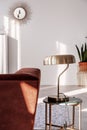 Stylish golden lamp on elegant side table next to comfortable sofa in trendy living room interior
