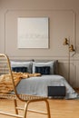 Stylish golden lamp next to king size bed with blue bedding and dark blue pillows