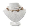 Stylish golden and pearl necklaces on jewelry bust against white background