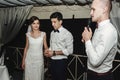 Stylish gorgeous bride and elegant groom with toastmaster at the wedding reception