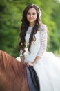 Stylish gorgeous happy brunette bride riding a horse on the back Royalty Free Stock Photo