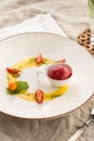 Stylish gourmet dessert with strawberry ice cream and fruit served on white plate at restaurant