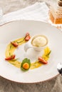 Stylish gourmet dessert with vanilla ice cream and fruit served on white plate at restaurant