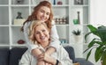 Happy grandmother and granddaughter friends hugging on couch at home