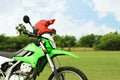 Stylish green cross motorcycle with helmet outdoors, space for text Royalty Free Stock Photo