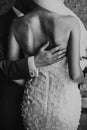 Stylish groom gently hugging beautiful bride back in city street. Gorgeous wedding couple of newlyweds sensually embracing at old Royalty Free Stock Photo