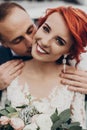 Stylish groom gently kissing his happy bride in neck at retro car and smiling. emotional romantic moment, space for text. luxury Royalty Free Stock Photo